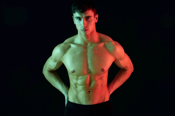 Hårdklippt med pumpade muskler bodybuilder fitness atletisk fysik neon ljus svart bakgrund — Stockfoto
