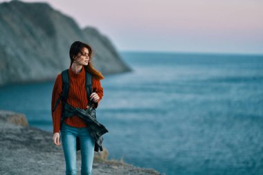 Sırt çantalı, kot pantolonlu bir kadın dağ manzarası modeli.