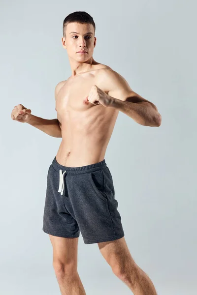 Atleet in korte gebaren met zijn handen op een grijze achtergrond en bodybuilders workout — Stockfoto