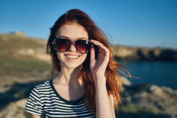 Radosna kobieta nosząca okulary słoneczne w górach na świeżym powietrzu w pobliżu morza — Zdjęcie stockowe