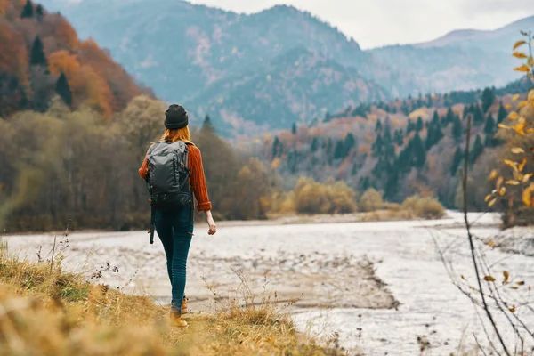 Femme sur la rive de la rivière dans les montagnes dans la forêt d'automne dans la nature vue arrière — Photo
