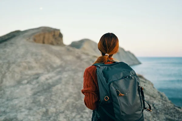 Красива жінка ходить з рюкзаком на спині в горах біля морської ландшафтної моделі — стокове фото