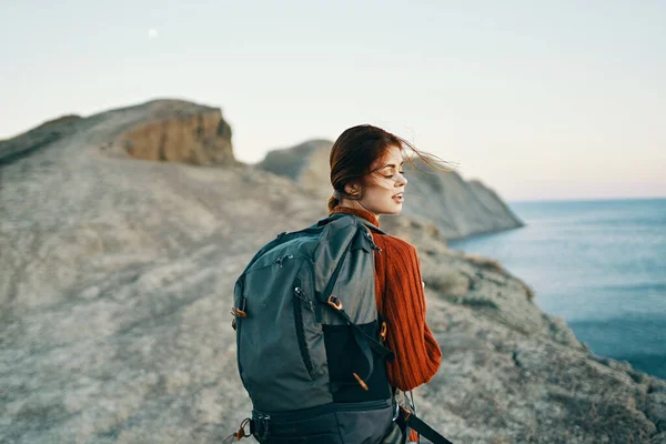 Schöne Wanderin mit einem Rucksack auf dem Rücken in den Bergen in der Nähe der Meereslandschaft Modell — Stockfoto