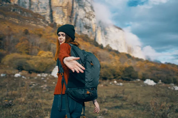 Vrouw wandelaar met een rugzak reist in de bergen buiten in de herfst gevallen bladeren — Stockfoto