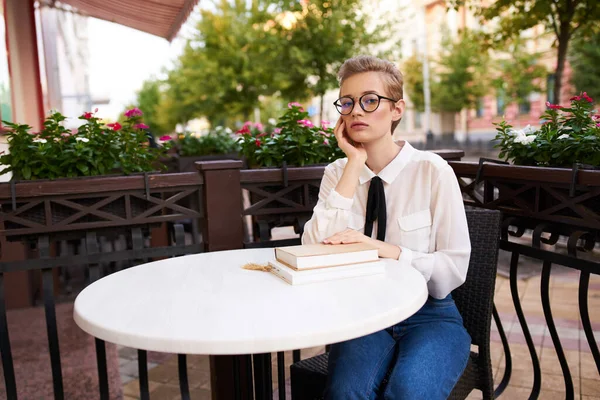 Γυναίκα με κοντά μαλλιά σε ένα τραπέζι σε ένα καφέ και βιβλίο εκπαίδευσης φοιτητής της επιστήμης — Φωτογραφία Αρχείου