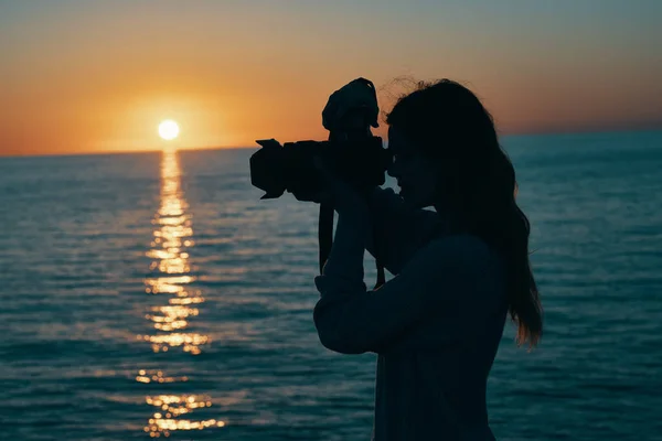 日落时在海边带着相机的女摄影师 高质量的照片 — 图库照片