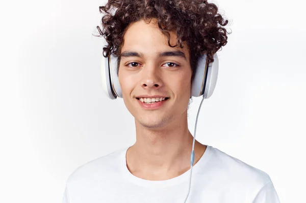 Guy with curly hair in a white t-shirt listens to music technology — Stock Photo, Image