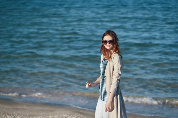 Mujer con abrigo y camiseta a rayas en la playa mar olas paisaje montañas —  Fotos de Stock
