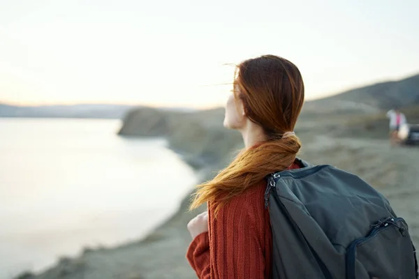 Жінка подорожує в горах в природі біля моря з рюкзаком на спині — стокове фото