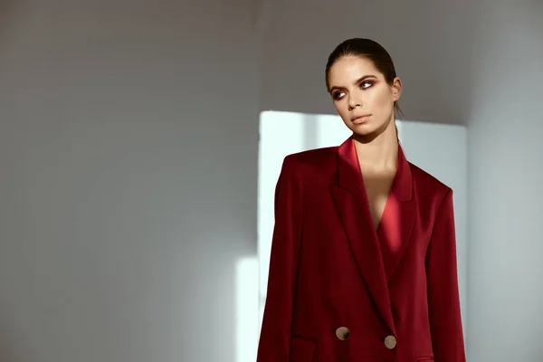 Senhora elegante em uma jaqueta vermelha com maquiagem brilhante em seu rosto olha para o lado — Fotografia de Stock