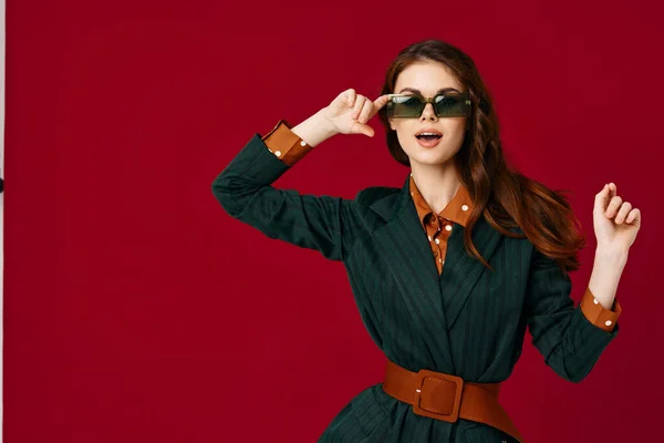 Όμορφη γυναίκα φορώντας γυαλιά ηλίου gesturing με τα χέρια μόδας περικοπεί προβολή κόκκινο φόντο — Φωτογραφία Αρχείου