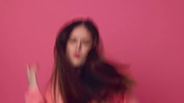 Young woman dancing and posing beautifully on a pink background in a pink sweatshirt — Stock Video