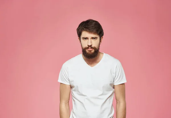 Hombre sobre un fondo rosa en una camiseta blanca emociones modelo recortado ver —  Fotos de Stock