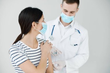 Omuz aşısı yapılan bir hastaya iğne yapan bir adam.