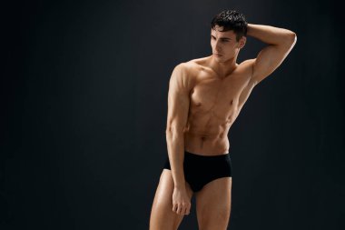 Kaslı kaslı, siyah stüdyo külotuyla poz veren sporcu.