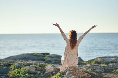 Denize yakın dağlarda elleri havada bir kadın. 