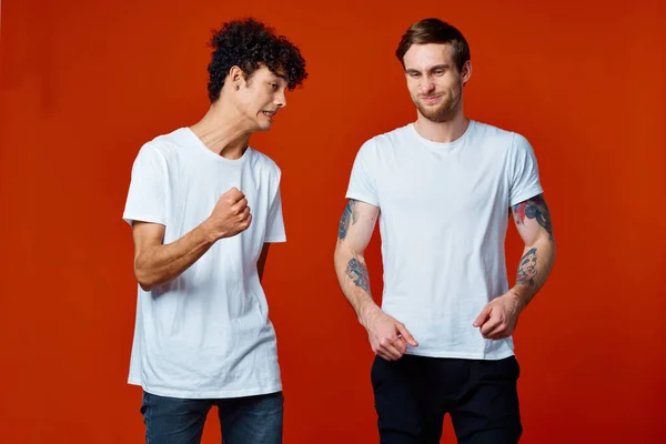 Due uomo in bianco t-shirt comunicazione amicizia rosso sfondo — Foto Stock