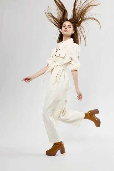 Щаслива жінка підскочила в білому комбінезоні і коричневому взутті — стокове фото