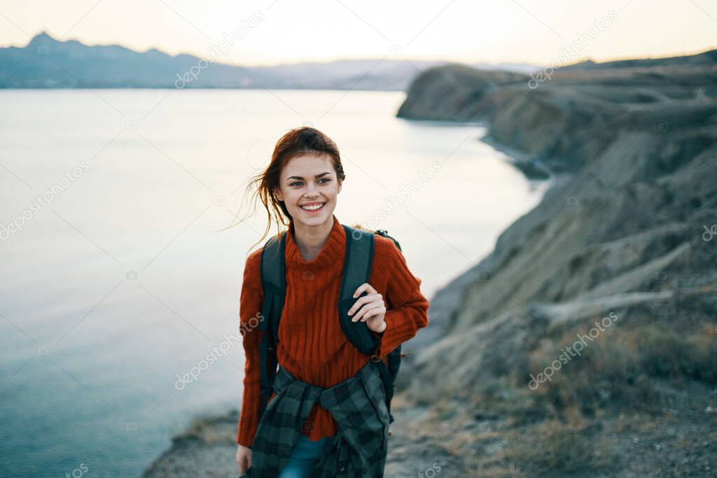 woman in a red sweater outdoors in the mountains by sea. High quality photo