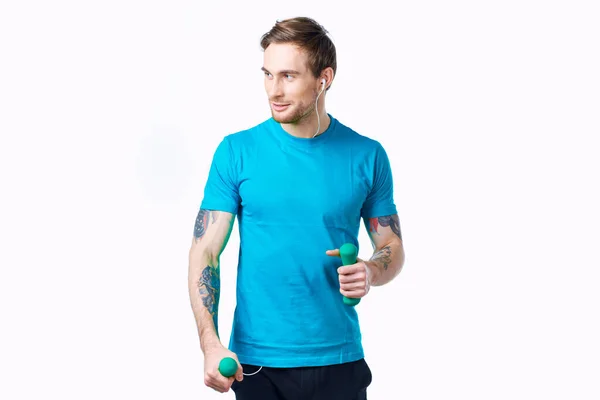 Homem de t-shirt azul com halteres no treino de fitness tatuagem mão — Fotografia de Stock