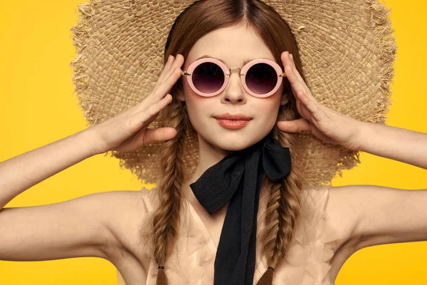 Güneş gözlüklü ve şapkalı güzel bir kadın yaz seyahati görüntüsü sarı arka plan — Stok fotoğraf