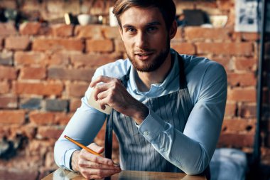 Kafede tezgahın arkasında barmen ve mavi gömlekli önlük menüsü.