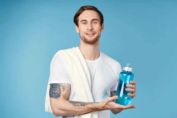 Uomo sportivo con tatuaggi sulle braccia bottiglia d'acqua blu allenamento — Foto Stock