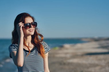 Güzel bir kadın, kızıl saçlı kumsalda dinleniyor. 