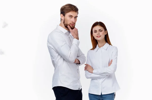 Empleados en el trabajo un hombre y una mujer en camisas idénticas sobre un fondo claro de pie uno frente al otro — Foto de Stock