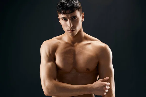 Männlicher Bodybuilder mit aufgepumptem Körper posiert vor dunklem Hintergrund — Stockfoto