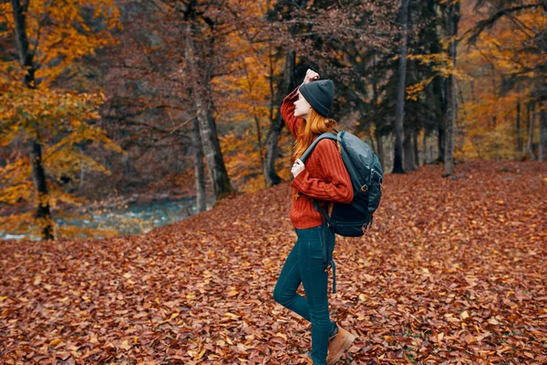 Mulher de viagem feliz com mochila caminha pelo parque de outono na natureza perto da paisagem do rio suéter de árvores altas — Fotografia de Stock