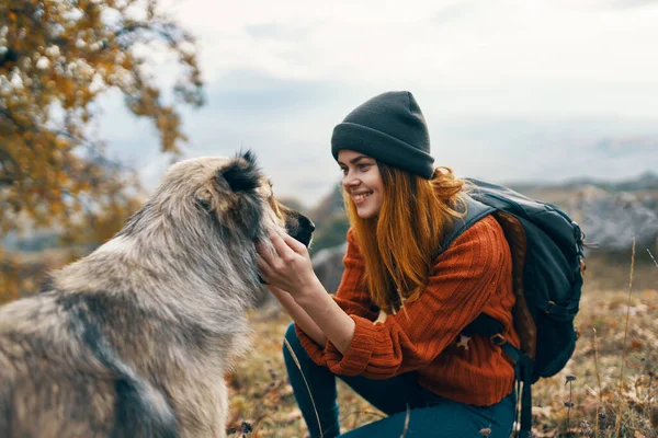 Весела жінка турист пестить собаку на відкритому повітрі ландшафтний відпочинок — стокове фото