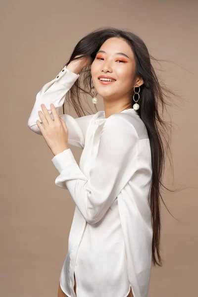 Женщина азиатской внешности яркий макияж белая рубашка бежевый фон роскошь — стоковое фото