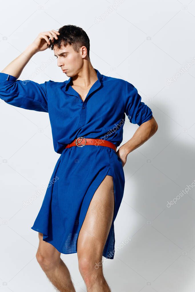 a young man in a blue dress with a red belt shows naked legs 