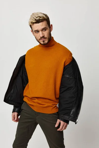 Legging in een oranje trui met een unbuttoned jack op de schouders en een licht achtergrondmodel — Stockfoto