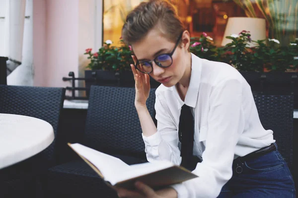 Utbildning kvinna i glasögon med bok vid bordet i café — Stockfoto