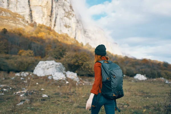 Donna con uno zaino passeggiate sulla natura in montagna in autunno cielo blu rocce paesaggio — Foto Stock
