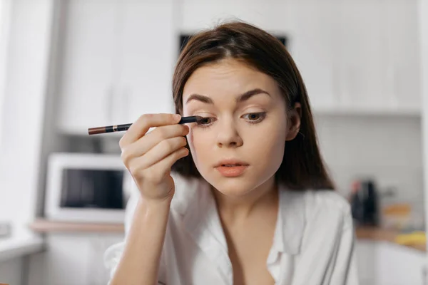 Vacker kvinna med eyeliner penna makeup kosmetologi rum — Stockfoto