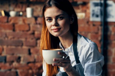 Güzel bayan garson elinde kupa duvar restoranı tutuyor.