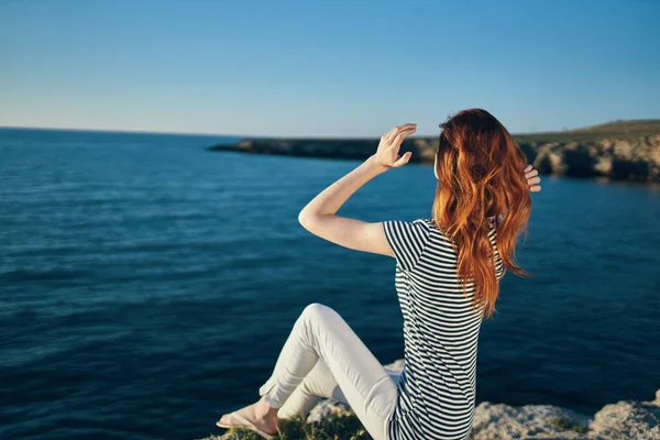 Viaggiatore felice in t-shirt e pantaloni in estate su una pietra vicino al mare in montagna paesaggio — Foto Stock