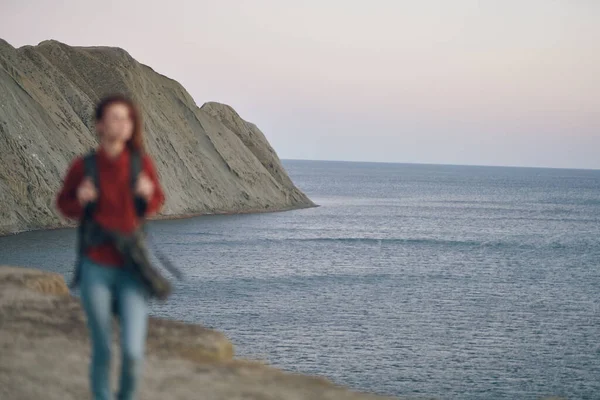 Woman hiker with backpack walking along the beach near the sea in the mountains — Stock Photo, Image