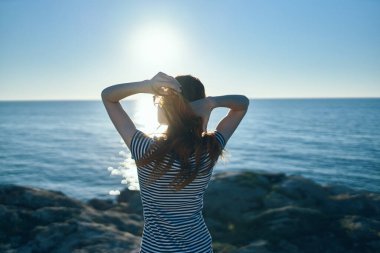 Kadın deniz kenarında, dağlarda, yazın doğada ve günbatımında, arka planda dinlenir.