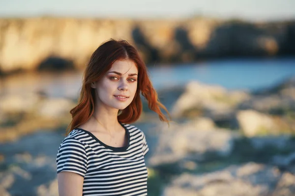 Retrato de uma mulher em uma camiseta listrada nas montanhas perto do rio na natureza — Fotografia de Stock