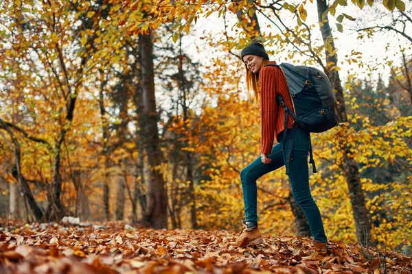 Schöne Frau mit einem Rucksack im Park auf Naturlandschaft gefallene Blätter von unten gesehen — Stockfoto