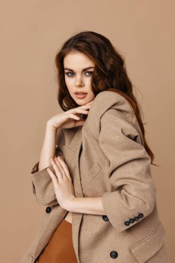 Palto giymiş güzel esmer, göz kamaştırıcı ev bej arka plan.