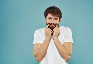 Mavi arka planda sakallı genç bir adam. Duygusal model korkmuş görünüyor.