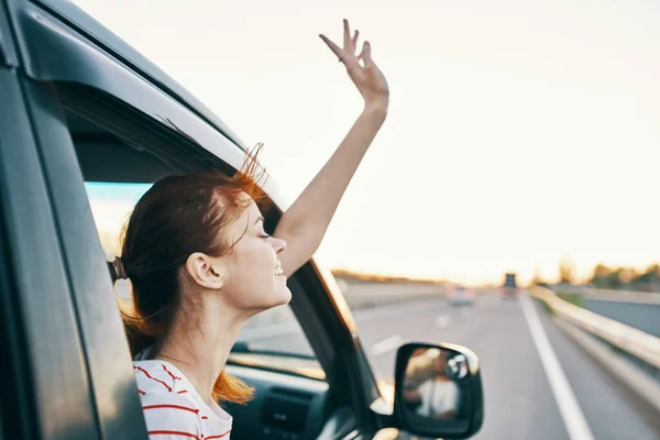 Mulher alegre com cabelos vermelhos olha para fora da janela do carro na estrada em férias de verão relaxar — Fotografia de Stock