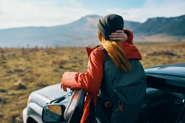 자연 속에서 자동차 문 근처에 가방을 들고 있는 모자를 쓴 여행자 — 스톡 사진