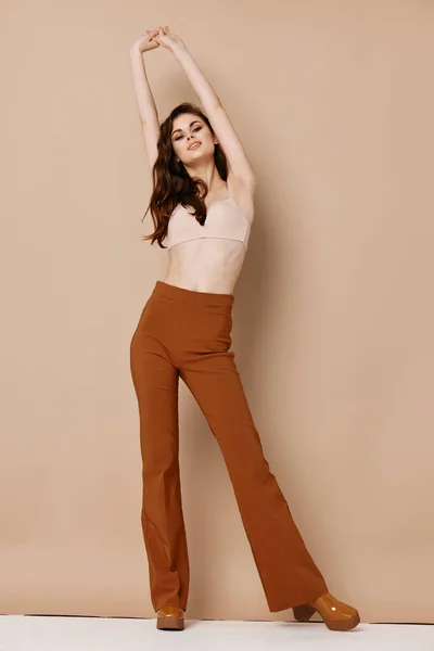 Nude woman in bra pants raised her hands up on a beige background — Stock Photo, Image