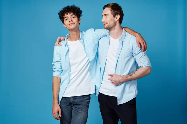 Giovani uomini in camicie blu abbracciare su sfondo isolato amici divertimento — Foto Stock